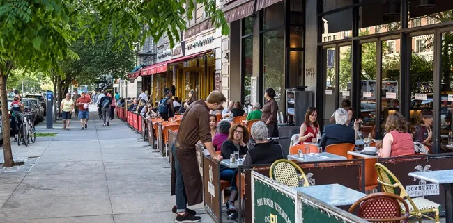 Angled view of Broadway with customers eating outside of restaurants